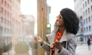 A stylish woman laughs while standing on a street lined with office buildings