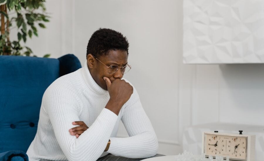 A man sits in front of a chess board thinking deeply.