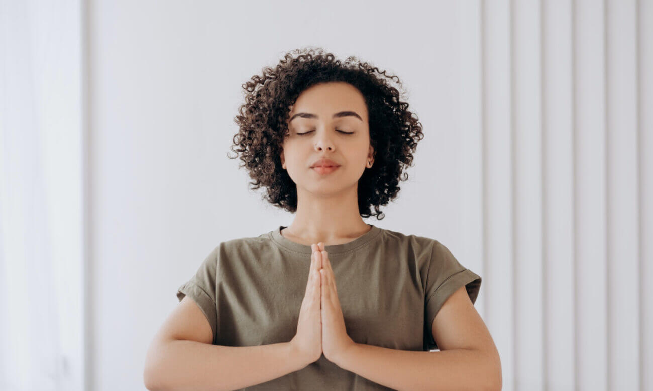 A young woman in a meditative pose breaths in deeply