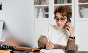 A woman takes notes while discussing inheritance rules with an advisor on the phone