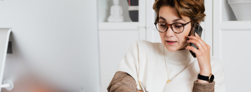 A woman takes notes while discussing inheritance rules with an advisor on the phone