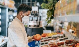 A man picks up an onion while shopping for groceries.