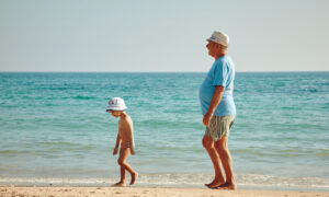 A man on the beach with his grandson, because he was able to apply for CPP Survivor's Pension benefit