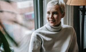 A middle aged woman sits by a window in a cafe