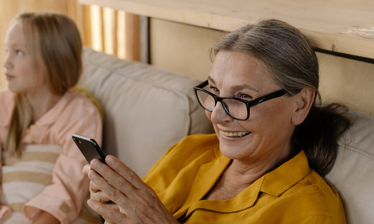 A middle-aged woman smiles as she sits on a couch near her niece