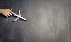 A hand pushes a model airplane across a chalkboard