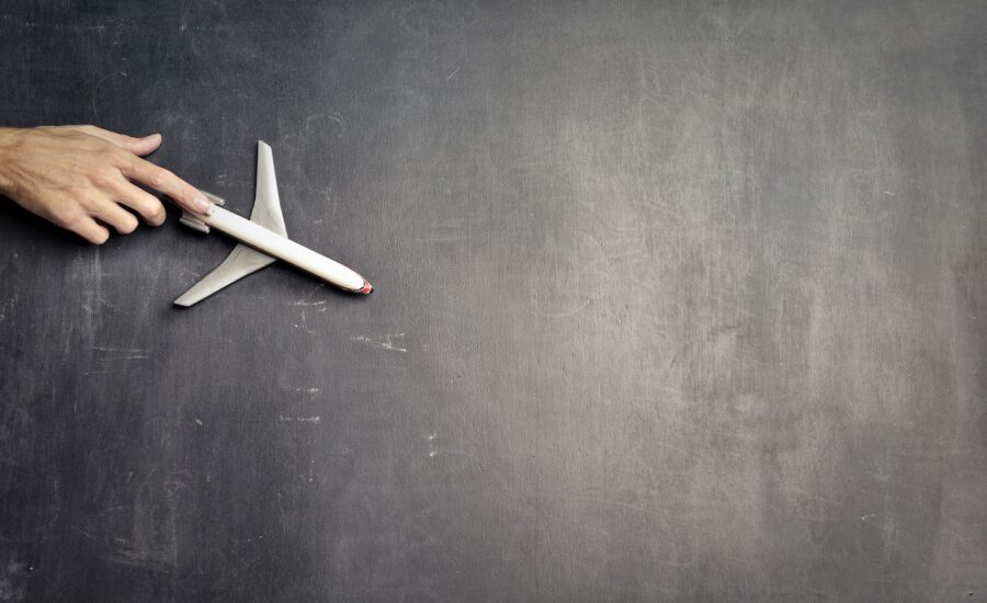 A hand pushes a model airplane across a chalkboard