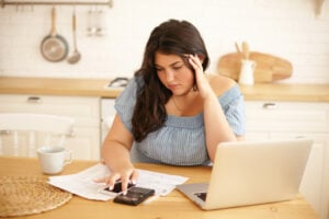 A young woman calculates her debts at the kitchen table