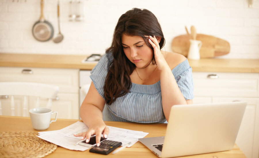 A young woman calculates her debts at the kitchen table