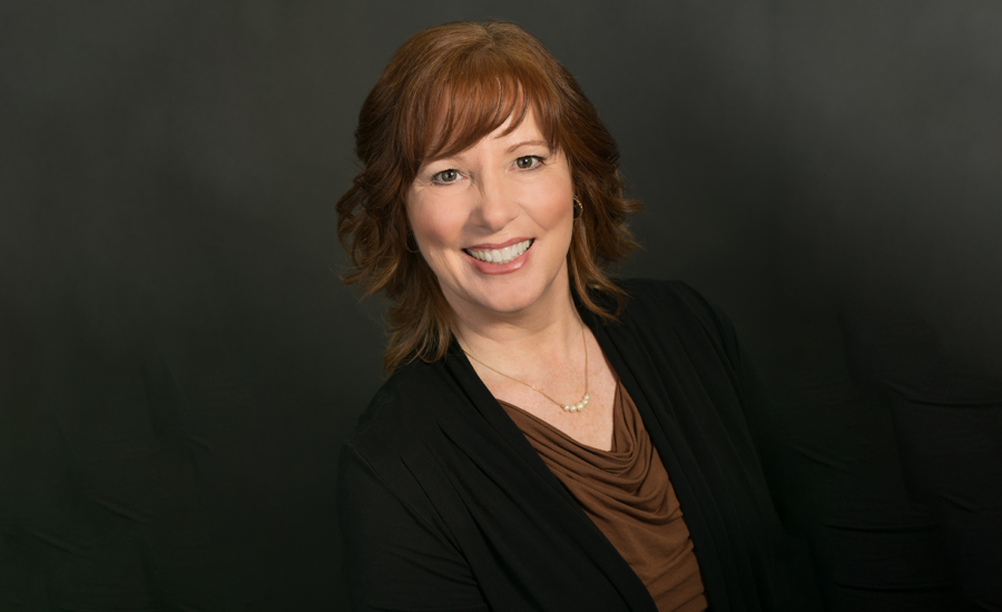 Financial Planner Janet Gray smiles at the camera against a dark background.