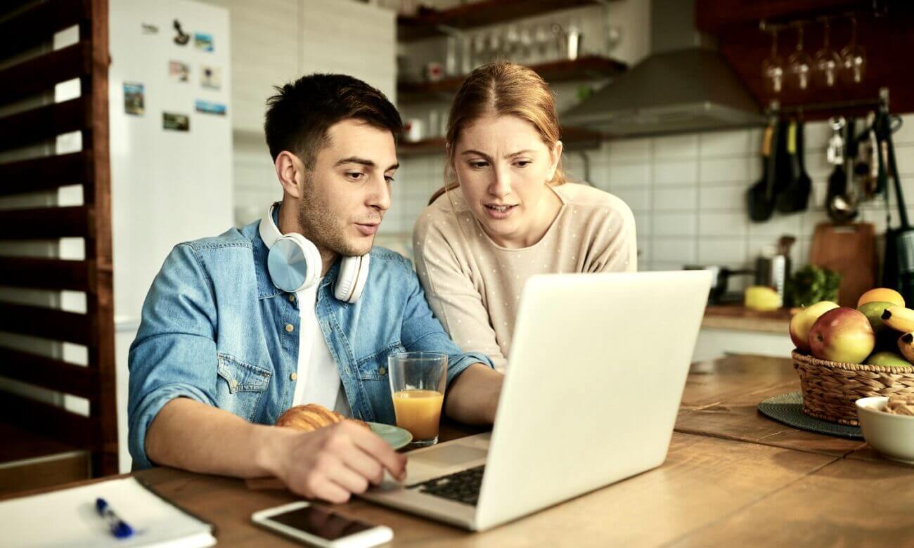 A young couple studies GIC rates on a laptop