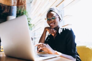 A young woman smiles as she buys a GIC on her laptop