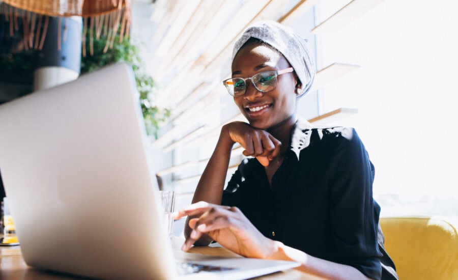 A young woman smiles as she buys a GIC on her laptop