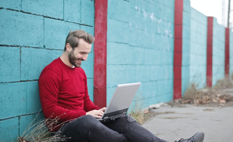 A man sits against a wall outside comparing FHSA rates online