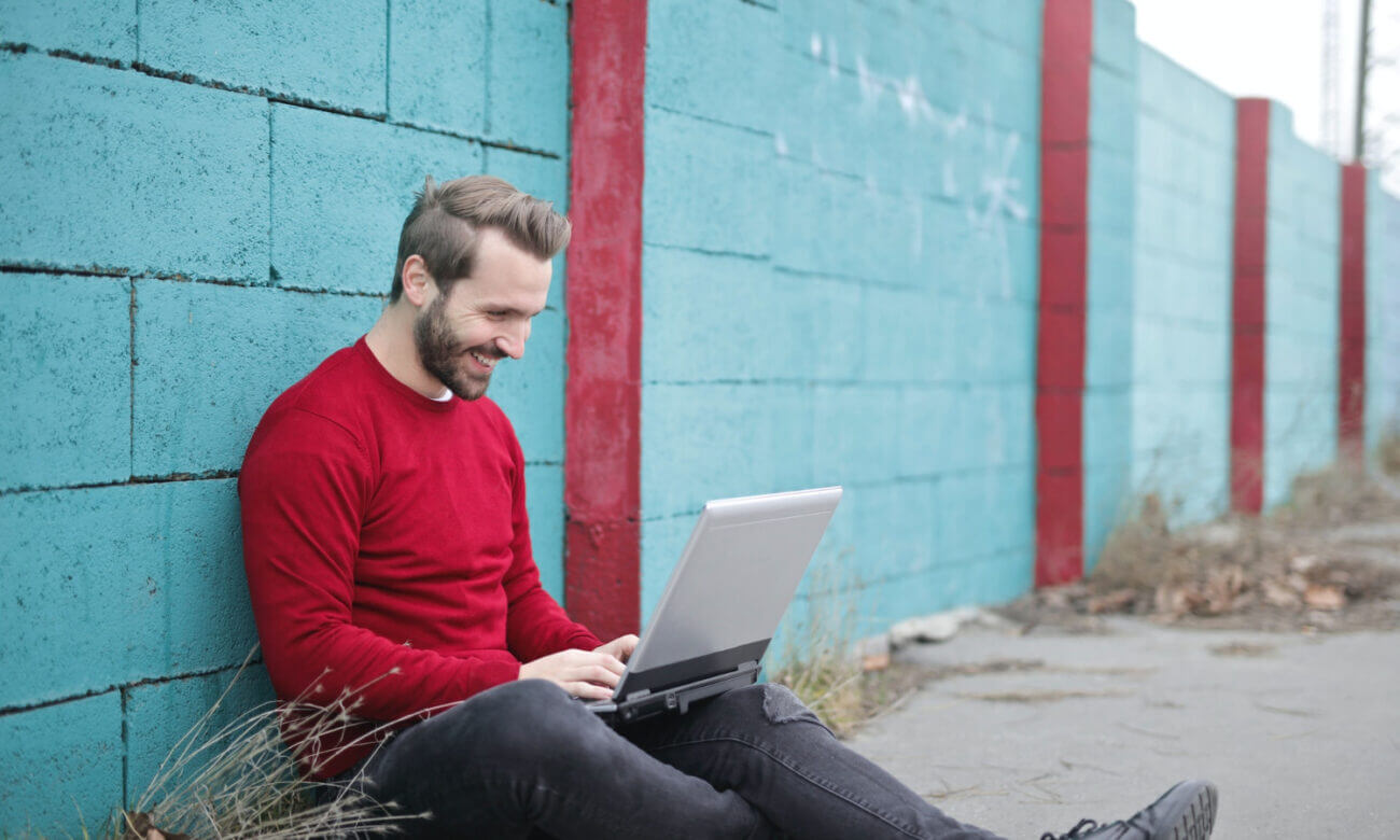 A man sits against a wall outside comparing FHSA rates online