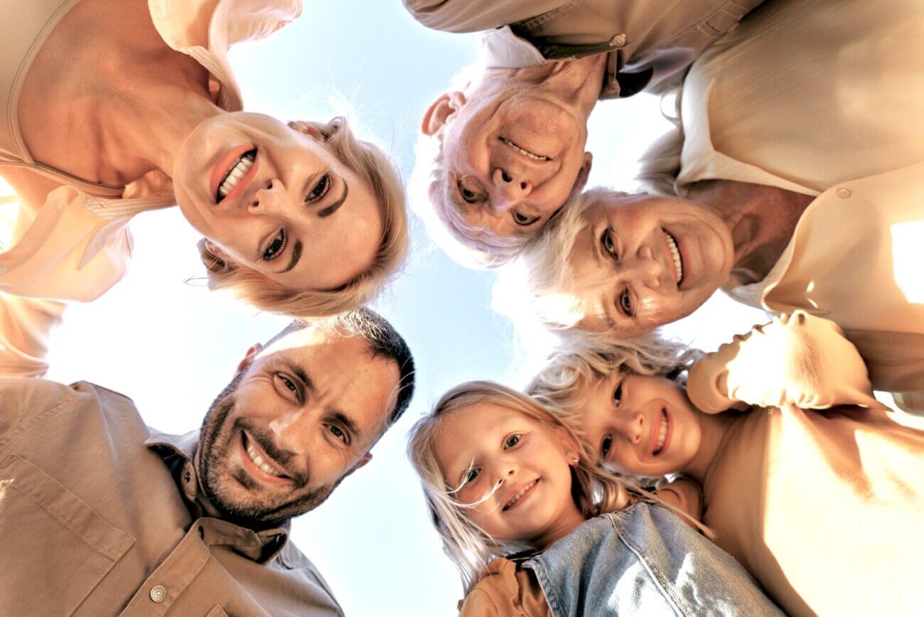 Two parents, two grandparents and two kids in a circle smile down at the camera