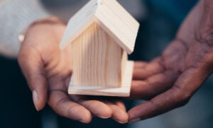 A man holds a miniature wooden home in his hands