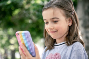 A girl smiles at her money-tracking app on a smartphone