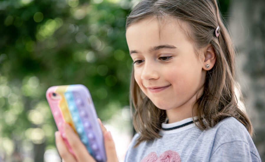 A girl smiles at her money-tracking app on a smartphone