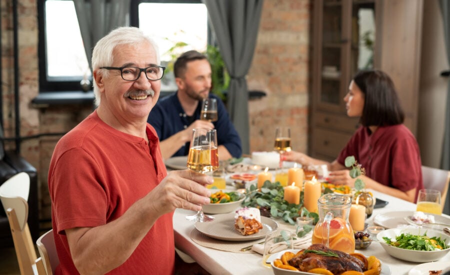 A smiling senior-age man at a dinner table with his adult son and daughter