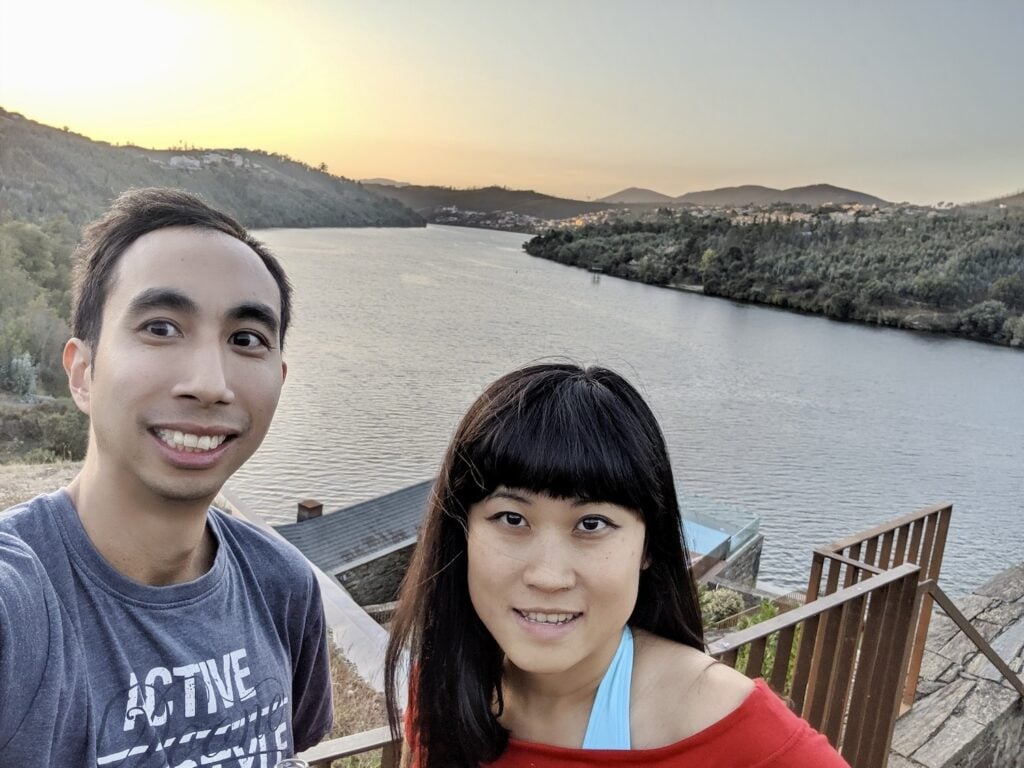 A young man and woman smile beside a wide river