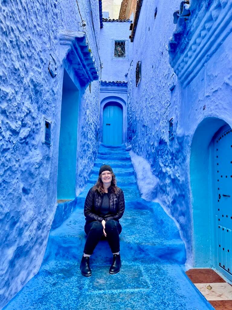 Meghan Bailey sits on a blue staircase in Morocco