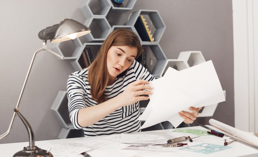 A young woman organizes papers on her desk