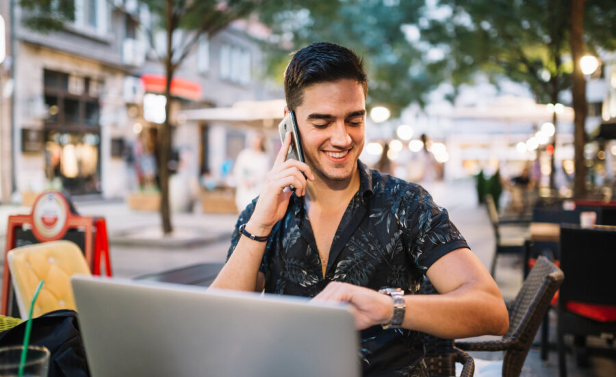 Young man works on his laptop at a European cafe