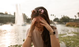 A woman facing financial decision fatigue rests her head in her hands, looking frustrated.