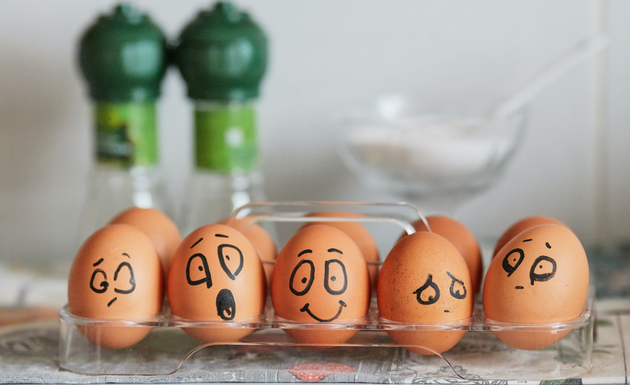 Eggs sit in a carton with different expressions drawn in black marker to represent investor behavior.