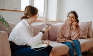 A young woman talks with a mental health care worker on a couch.