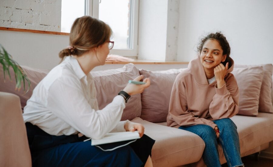 A young woman talks with a mental health care worker on a couch.