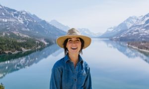 A woman who is happy about her move to Albertastands in front of the rocky mountains.