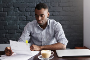 A young man looks at a stack of unpaid bills