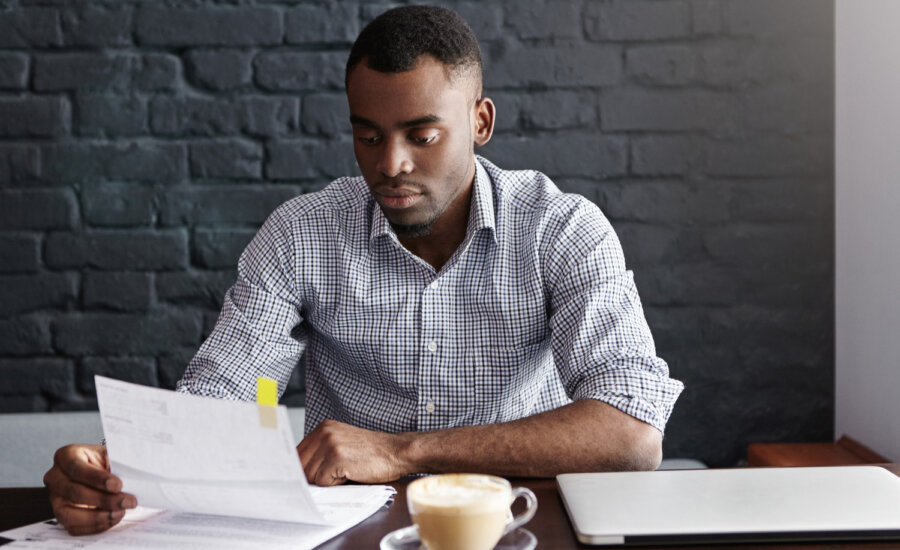 A young man looks at a stack of unpaid bills