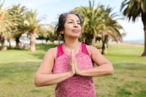 A middle-aged woman in active wear does yoga in a park