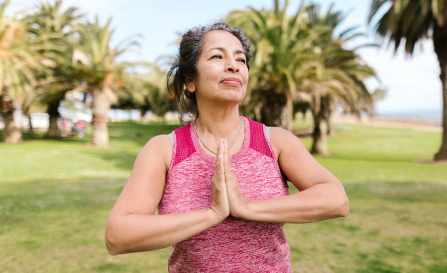 A middle-aged woman in active wear does yoga in a park
