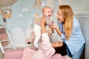 Two moms play with a baby in a nursery