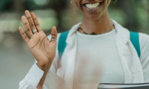 A young woman waves goodbye