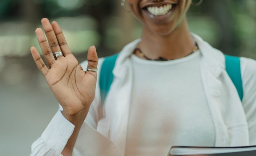 A young woman waves goodbye