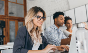 Three diverse young computer programmers work on laptops