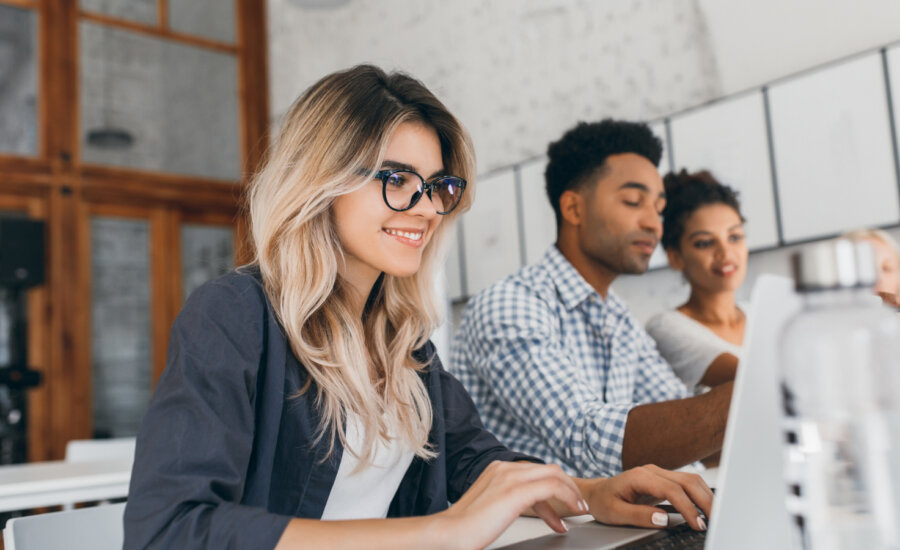 Three diverse young computer programmers work on laptops