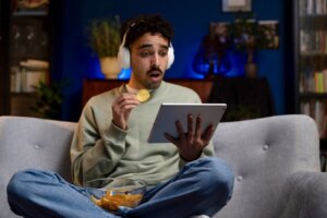 A young man looks shocked as he watches Netflix on a tablet