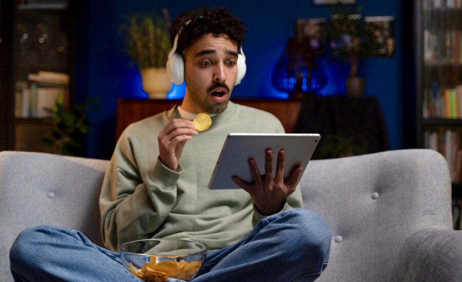 A young man looks shocked as he watches Netflix on a tablet