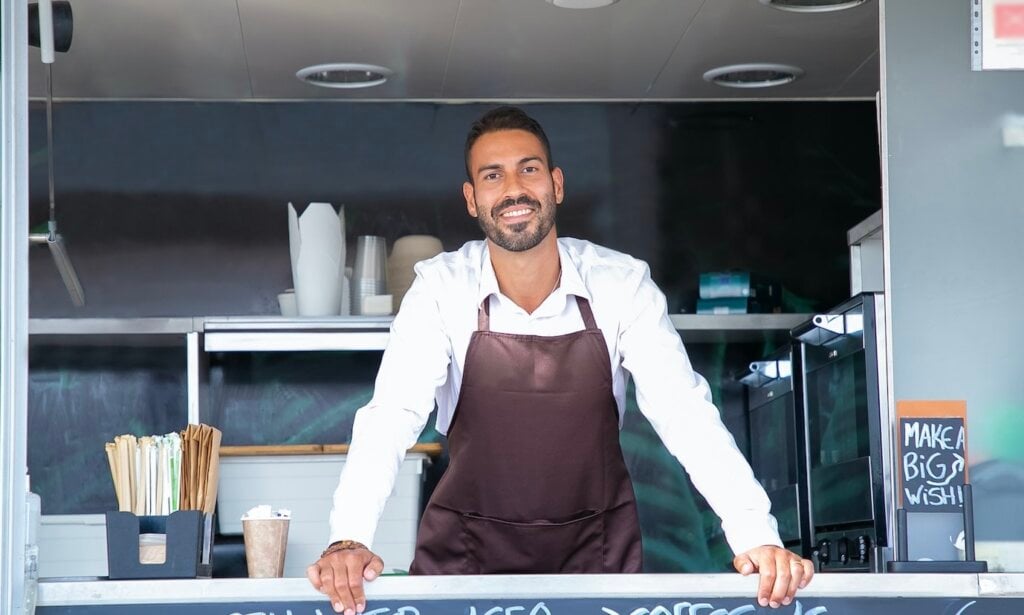 A smiling young man behind the counter of a food truck