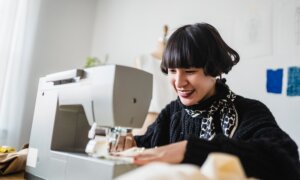 A smiling young woman works on a sewing machine