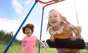 Two young girls play on the swings