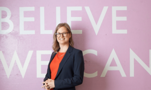 Kristine Beese in front of a mural saying "Believe We Can"