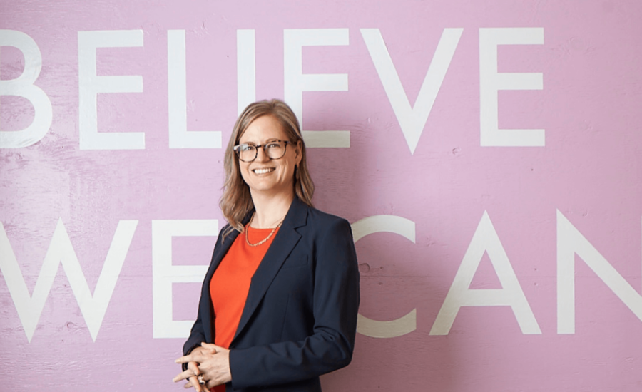 Kristine Beese in front of a mural saying "Believe We Can"