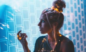 A woman's face is illuminated by the glowing lights of a computer system